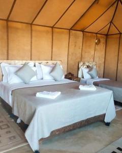 梅尔祖卡Sahara Luxurious Camp的帐篷内的两张床,配有白色床单