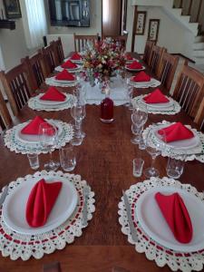 圣若昂-德雷Aconchego Mineiro的一张长桌,上面有红色的餐巾和眼镜