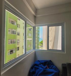 桑托斯Apto em frente a praia de Santos (Canal 5)的客房设有2扇窗户,前面设有1张蓝色的床。