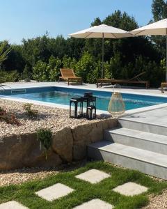 格鲁达Meridiem Holiday Home in Dubrovnik region的一个带桌子和遮阳伞的游泳池