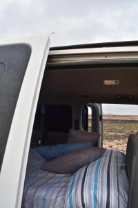 TetirFurgoCamper Van H1的一张位于带枕头的面包车后面的床铺