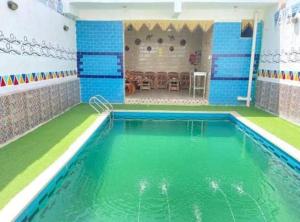 阿斯旺Bakar House的一座铺有绿色和蓝色瓷砖的室内游泳池