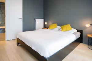 奥斯坦德Vakantieappartement Oosteroever Oostende的一间卧室配有一张带黄色枕头的大床