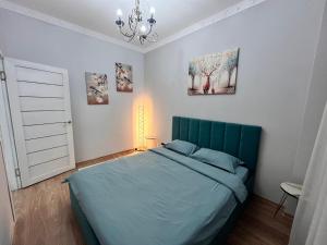 阿拉木图2-х комнатная в Золотом квадрате的一间卧室配有蓝色的床和吊灯。