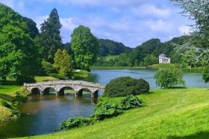 沃明斯特Large historic family home nr Longleat and Bath的公园里一座湖上的桥梁