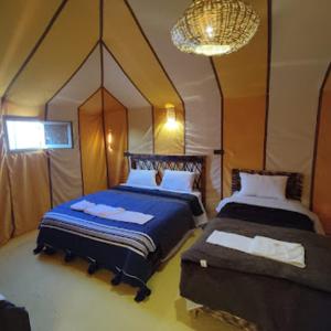 梅尔祖卡Blue Sky Luxury Camp的一间卧室配有两张床和吊灯。