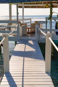 阿瓦托鲁Motu Fara Private Island的海滩上木板路,配有桌子和长凳
