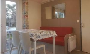 Plomeur澜汶露营酒店的一间带桌子和红色沙发的用餐室