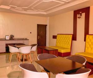 贝宁城Bosanic Hotel的配有桌椅和黄色椅子的房间