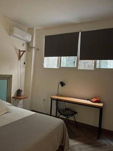 蒙得维的亚Acogedor apto en centro de Montevideo的一间卧室配有一张桌子、一张床和一个窗户