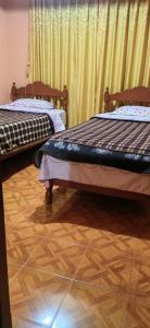 瓦拉斯Villa hospedaje的客房内设有两张床,配有木地板和窗帘