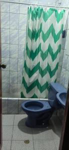 瓦拉斯Villa hospedaje的浴室里设有蓝色的厕所,配有绿色和白色的淋浴帘