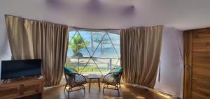 卢纳将军城Malipaya Villas的客厅设有大窗户、椅子和桌子