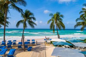 基督教堂市Turtle Beach by Elegant Hotels - All Inclusive的海滩上,有椅子和棕榈树,还有大海