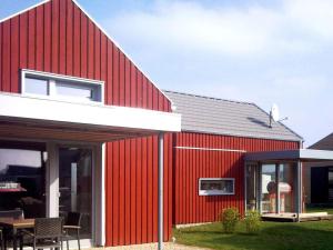 齐罗Lovely apartment in Immenstadt的红色的房子,有白色的屋顶和庭院
