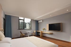 婺源Anlan Hotel Shangrao Wuyuan Cultural Plaza的一间卧室配有一张床和一台平面电视