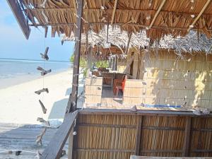 Kribyuk Beya homestay的海滩上的小屋,鸟儿飞过