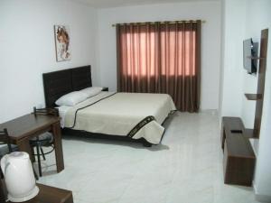 安曼Salvador Dali Apartments的一间卧室配有一张床、一张书桌和一个窗户。