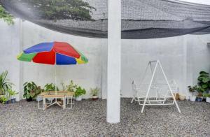 班达楠榜Oemah Ratu Hostel Syariah RedPartner的庭院配有桌子、多彩的遮阳伞和椅子