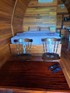 拉威海滩Seaview Eagles Nest Cabins的木房的一张床位,配有两把椅子