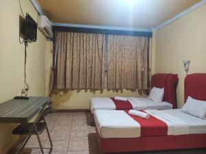 占碑市RedDoorz Syariah At Hotel Matahari 1 Jambi的客房设有两张床、一张桌子和一台电视。