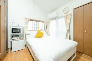福冈Rooms箱崎的卧室设有一张白色大床和一扇窗户。