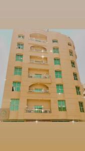 阿吉曼Lotus Furnished Hotel Apartments LLC. Ajman的一座高高的建筑,设有窗户和阳台