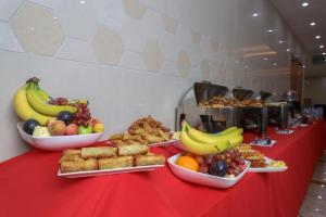Al KhānALAZMI HOTEL的红色的桌子上放着一碗水果和食物