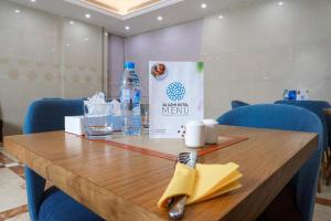 Al KhānALAZMI HOTEL的一张带一瓶水和餐巾的木桌