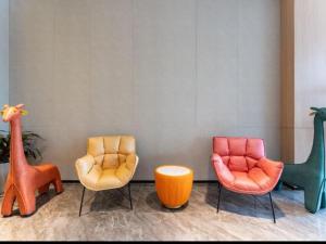 济南GreenTree Inn Jinan West Station Exhibition Center的一间房间,房间内设有3张不同的彩色椅子
