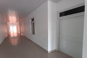 BanualuhuOYO 92504 Guesthouse Porsea的一条带白色墙壁的走廊和车库门