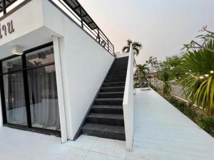 Ban Don Chaiเฮือนคำเเก้วรีสอร์ท & KK House cafa nan的通往白色建筑的楼梯,设有玻璃门