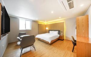 庆州H Avenue Gyeongju的一间卧室配有一张床、一台电视和椅子