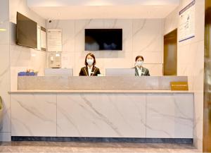 安顺City Comfort Inn Anshun West High Speed ​​Railway Station Huangguoshu Street的两个女人在柜台戴面具