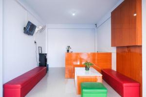 LaweanUrbanview Syariah Wisma Nabil Solo的一间设有红色和绿色长椅和桌子的房间