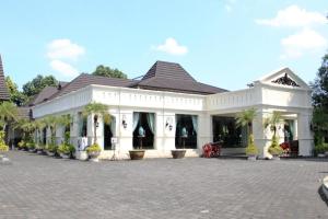LaweanUrbanview Syariah Wisma Nabil Solo的一座白色的大建筑,在庭院里种有棕榈树