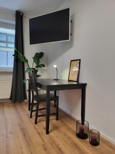 新乌尔姆ALA Living Stadt-Schwärmer Apartment 10min zum Ulmer Münster & Ulmer Altstadt, WLAN & Arbeitsplatz的一张带椅子的黑桌和墙上的电视