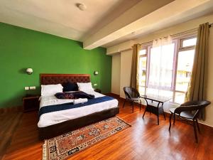 佩林DISHA SILVER PEAK Hotel的绿色卧室配有床和桌椅