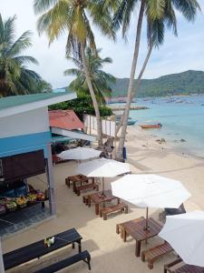 停泊岛Perhentian Bay Chalet的棕榈树海滩,海滩上摆放着桌椅