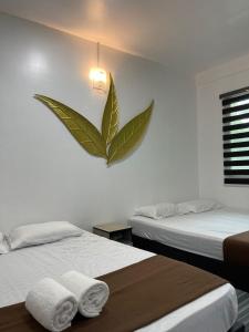 停泊岛Perhentian Bay Chalet的卧室配有两张床,墙上有一根大叶