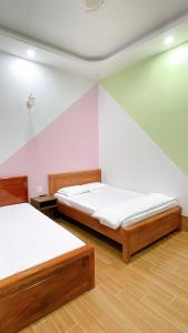 Xóm Tràm CửaNhà Nghỉ Thảo Tiên的配有粉红色墙壁和木地板的客房内的两张床