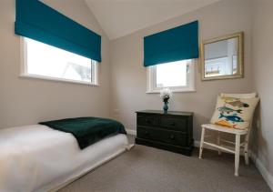 阿伯索赫Lluesta Cottage的一间卧室配有蓝色窗帘、一张床和椅子