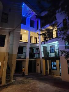 BulengaEQUATOR GATES HOTEL的一座建筑,晚上有一个人站在它前面