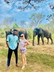 达瓦拉维Sheran Safari House的站在大象前面的男人和女人