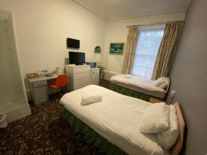 阿伯丁Aaran Central Guesthouse的一间卧室设有两张床、一张桌子和一个窗口。