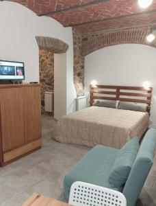 佩夏Casa in Bocca al Fiume的一间卧室配有一张床、一张沙发和一台电视。