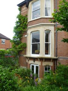 切尔滕纳姆Laurel House的砖屋,带两个窗户和灌木丛