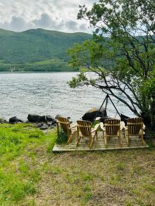 特罗姆瑟Unique stay 20 min from Tromsø with SUP and boat rental的一组椅子,坐在水边