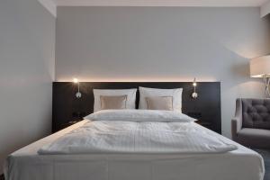 明登明登林佳特酒店 的卧室配有一张白色大床和一把椅子