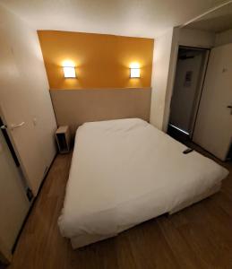 维也纳Hotel HECO Lyon sud Vienne的卧室配有白色的床和墙上的2盏灯。